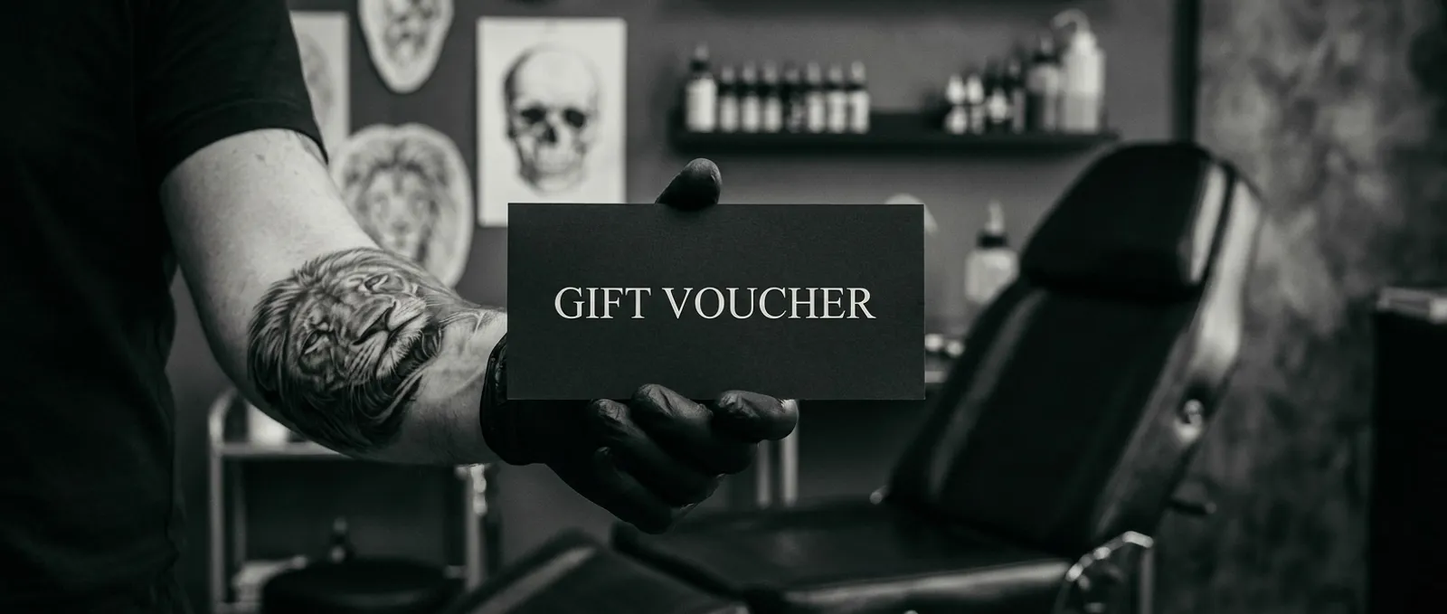 A black Liam Rebel Tattoos gift voucher held out by a tattooed, gloved hand in the Chapeltown studio