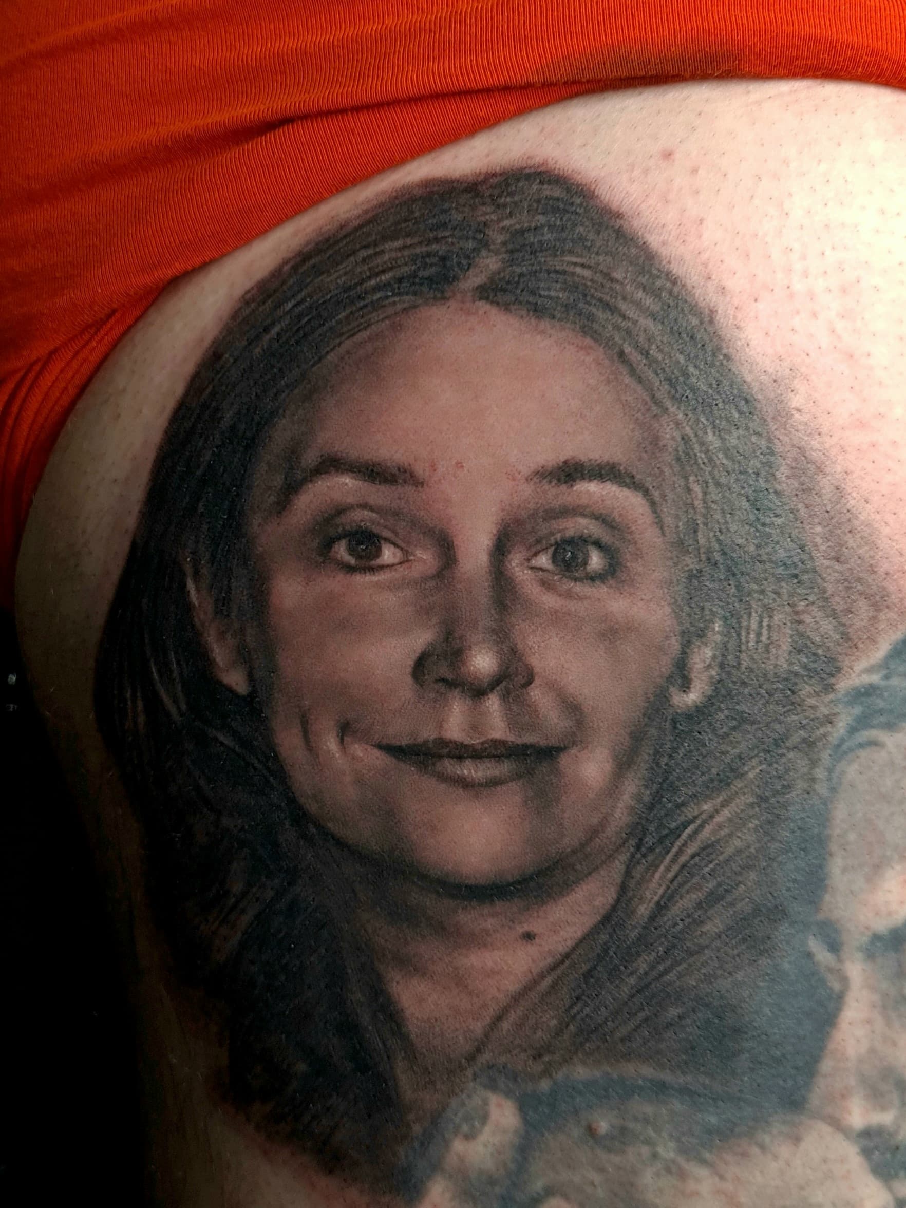 Realistic black and grey portrait tattoo of a smiling woman on skin.