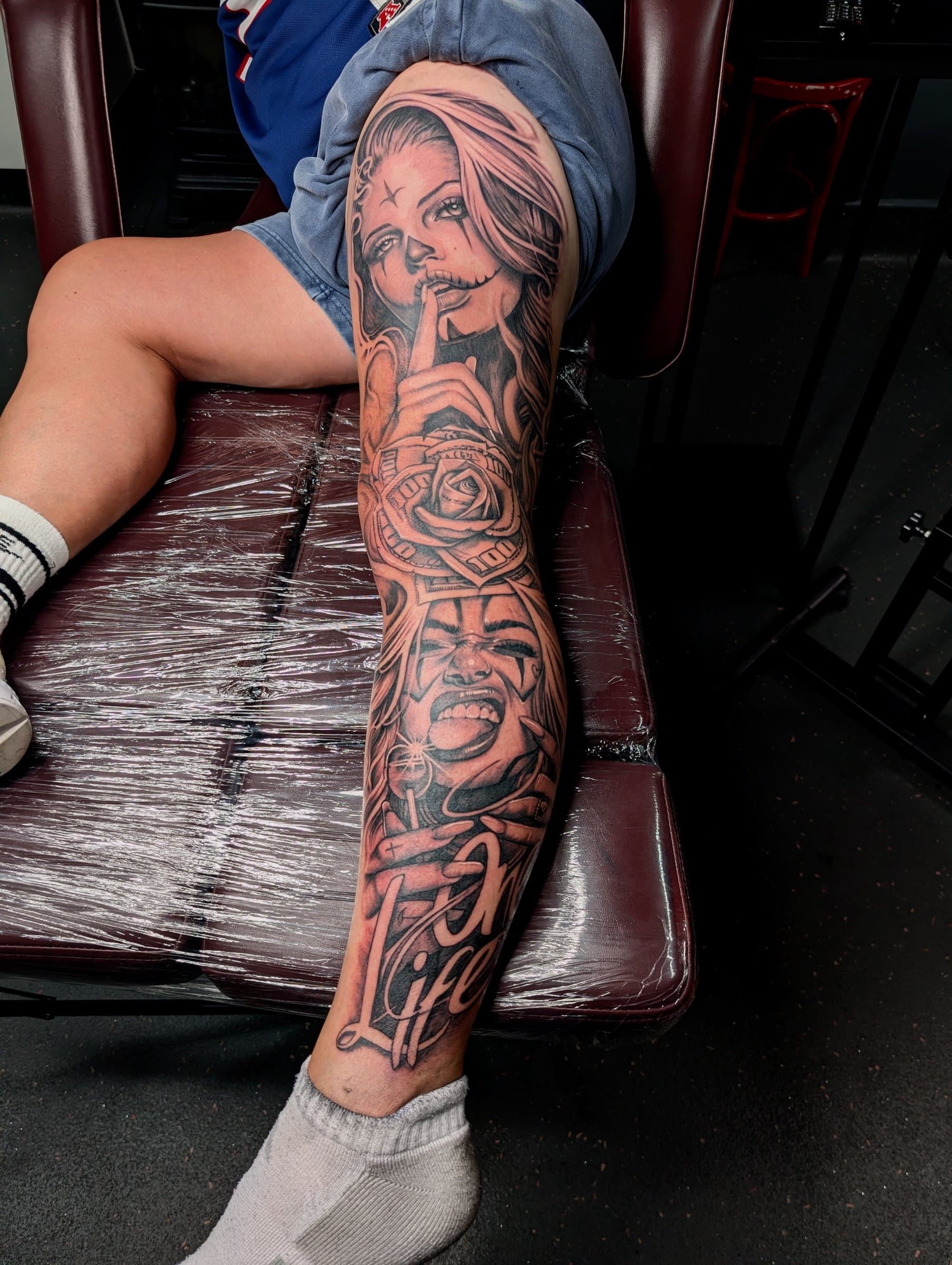 Black and grey realism leg sleeve tattoo of two women's faces, a rose and script text