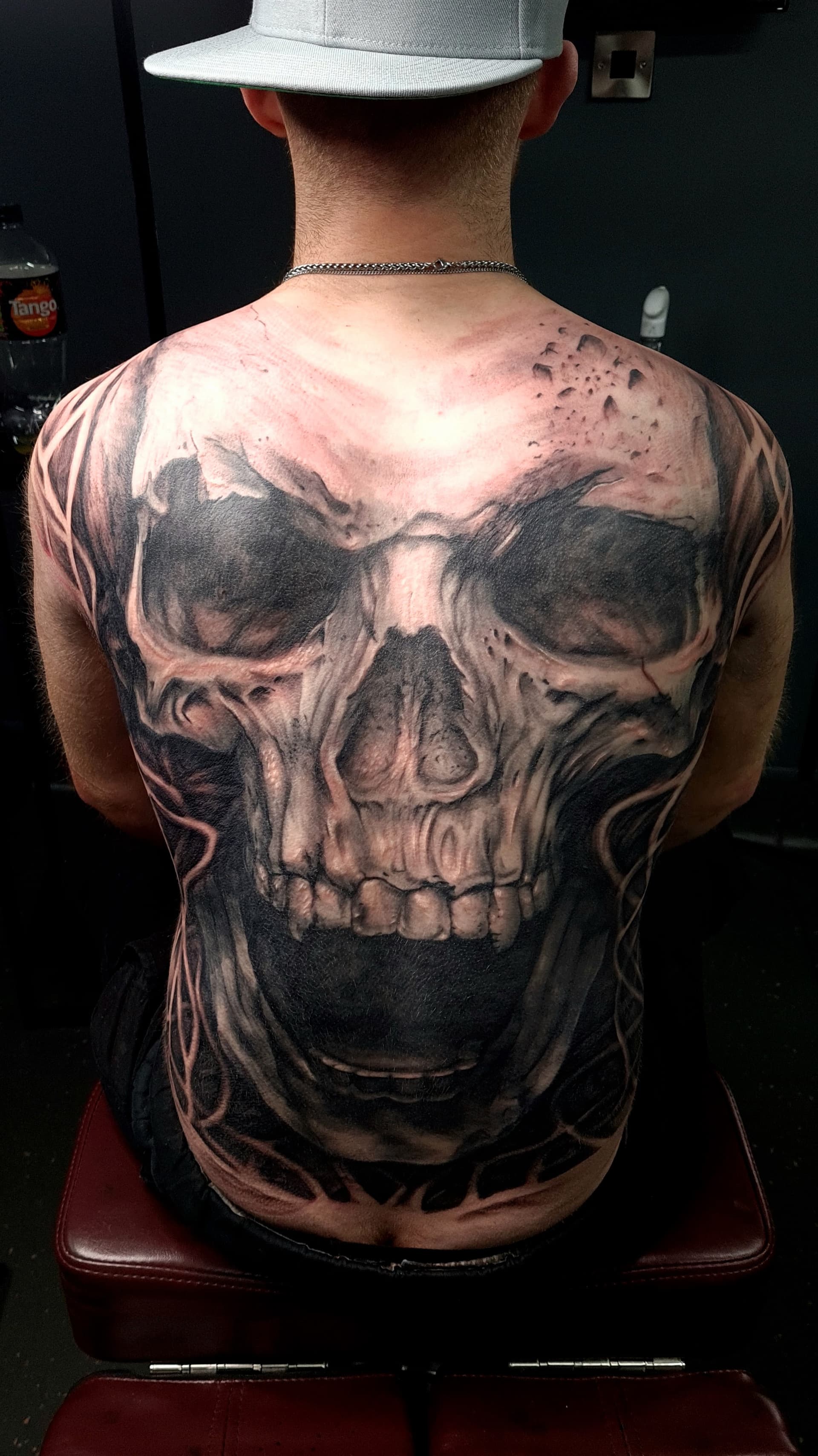 Black and grey realism tattoo of a large skull covering a man's full back