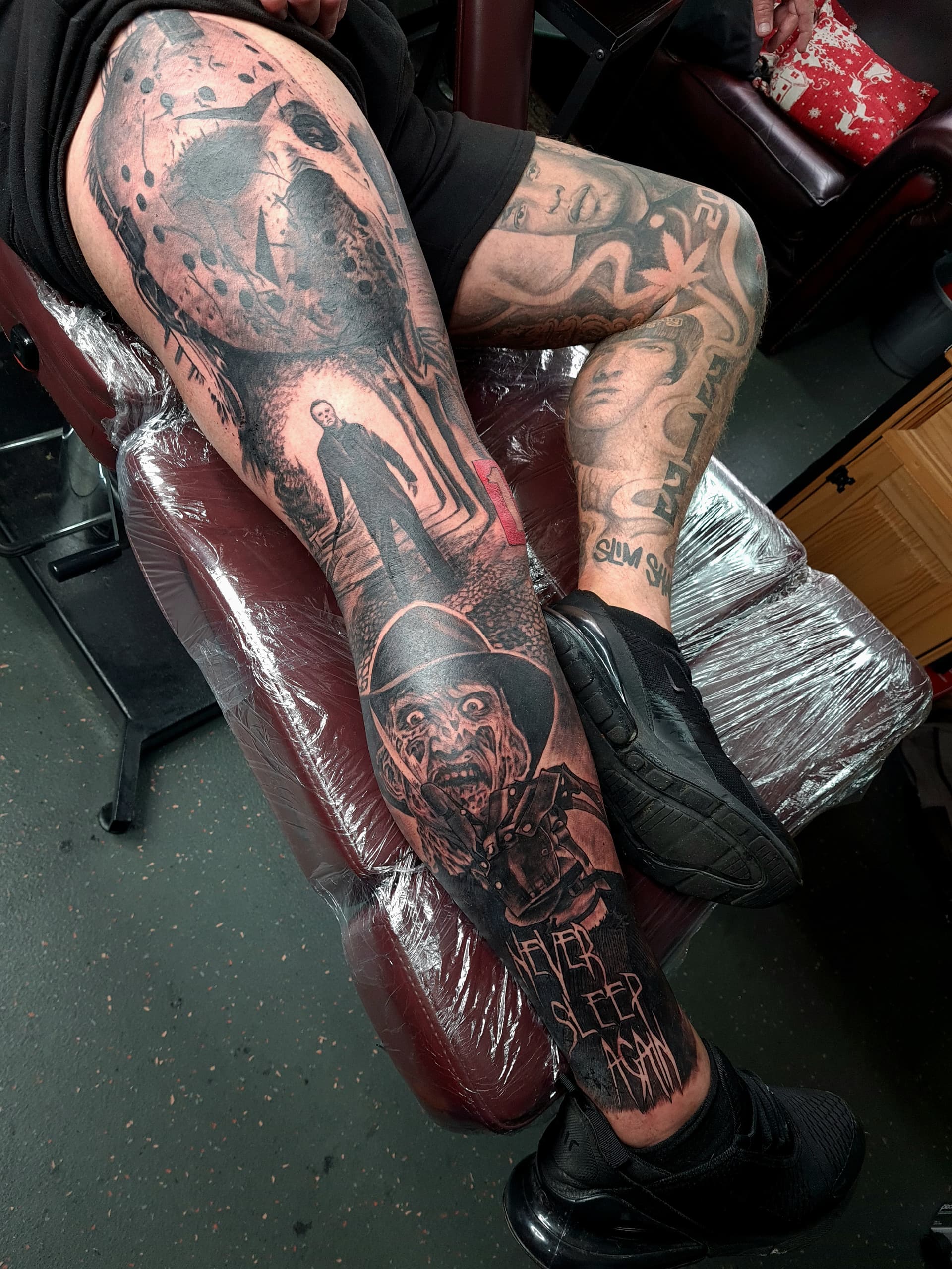 Black and grey realism leg sleeve tattoo of horror film villains including Jason Voorhees and Freddy Krueger
