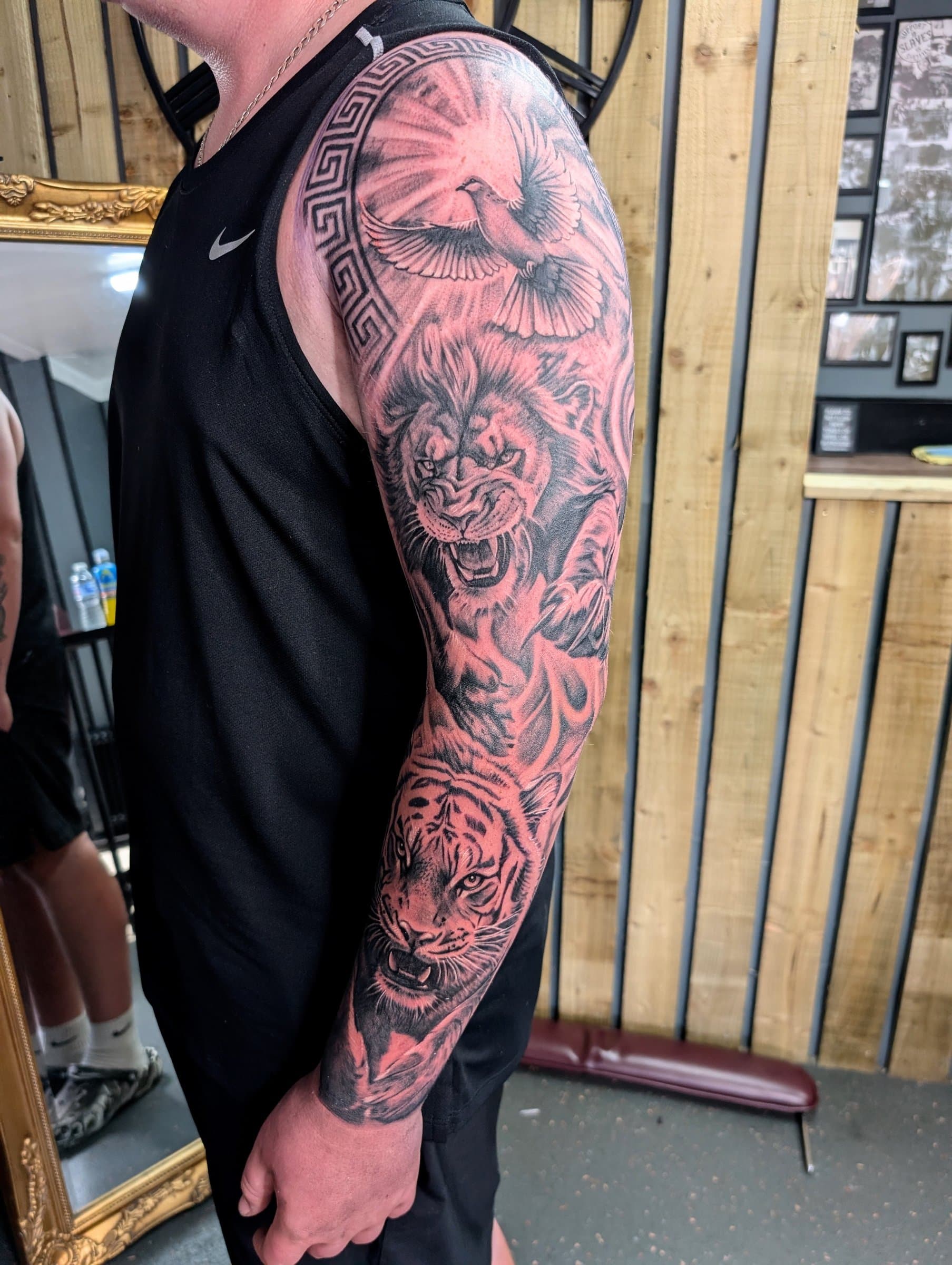 Black and grey realism tattoo sleeve featuring a lion, tiger and flying dove covering the full arm