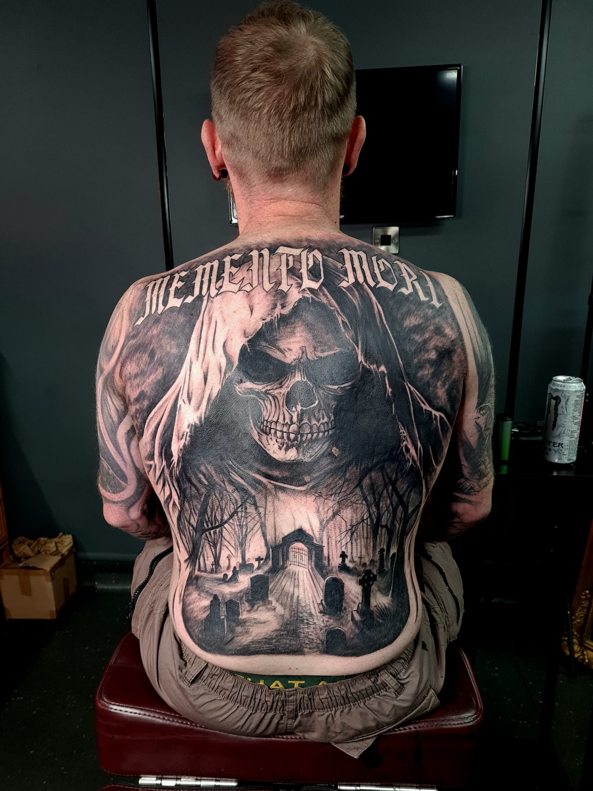 Black and grey realism tattoo of a skull, hooded figure and graveyard scene covering the full back