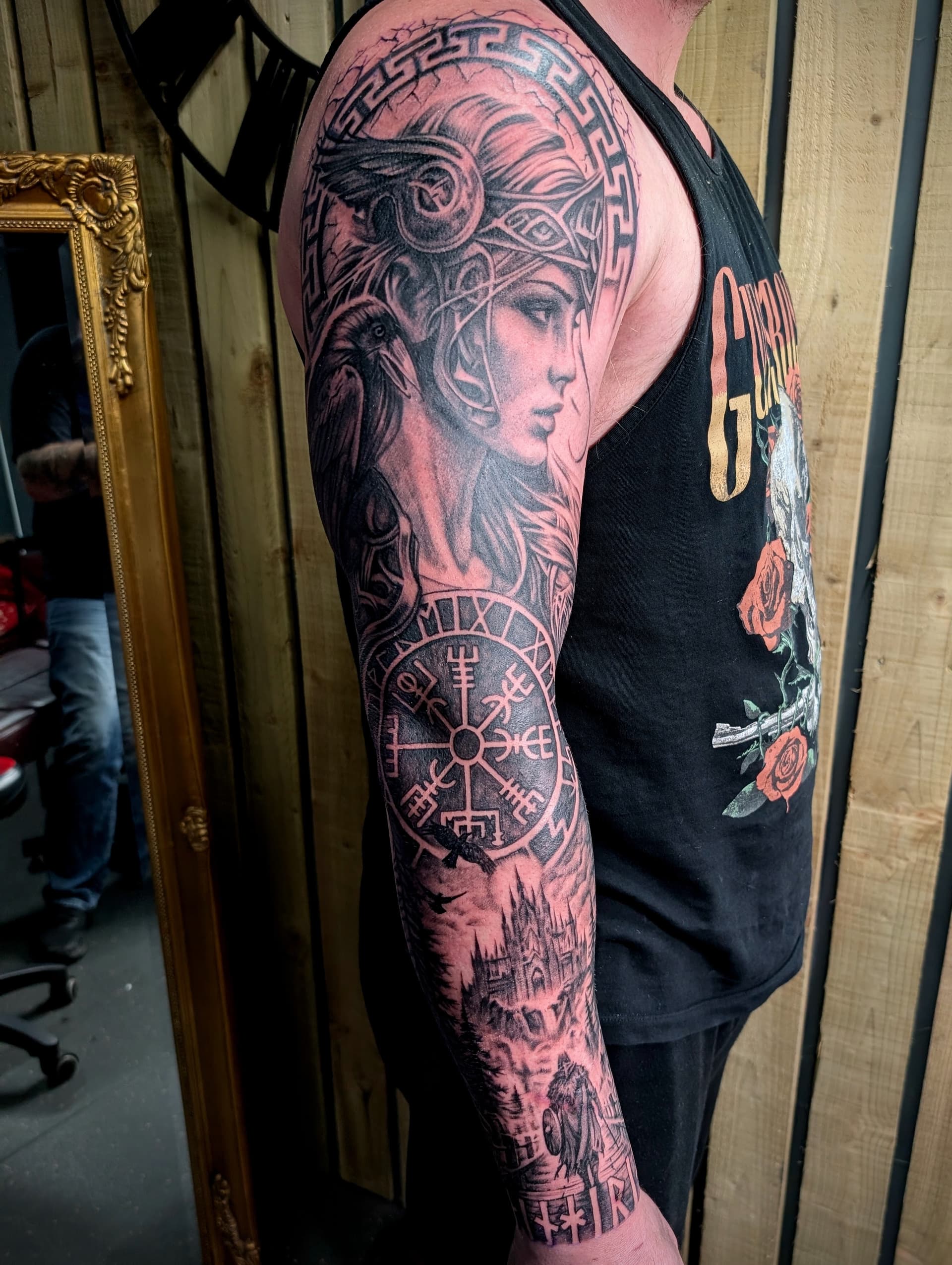 Black and grey realism arm sleeve tattoo of a Norse valkyrie, raven and Vegvisir compass with a castle