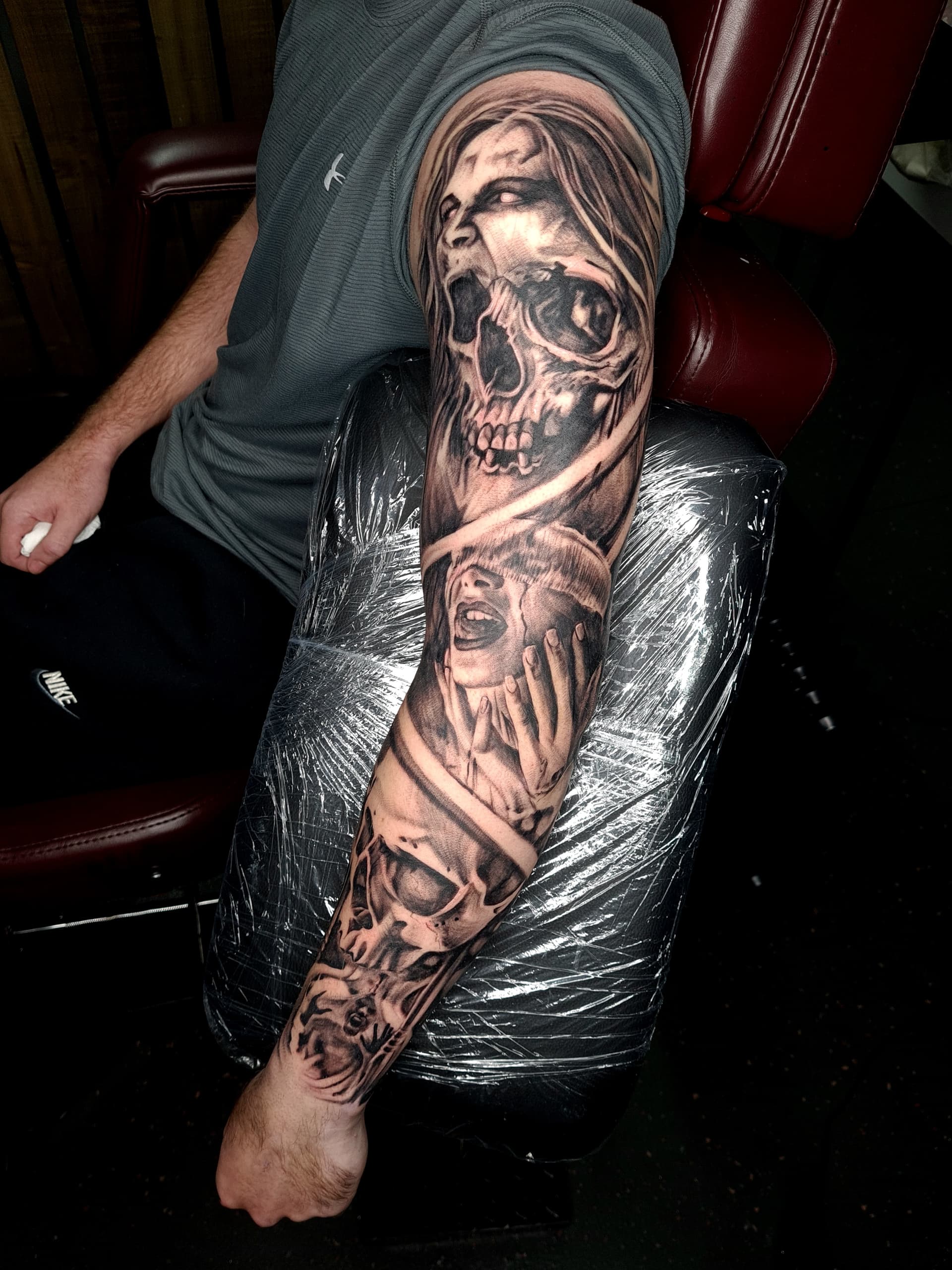 Black and grey realism tattoo sleeve of screaming faces and a skull covering the full arm